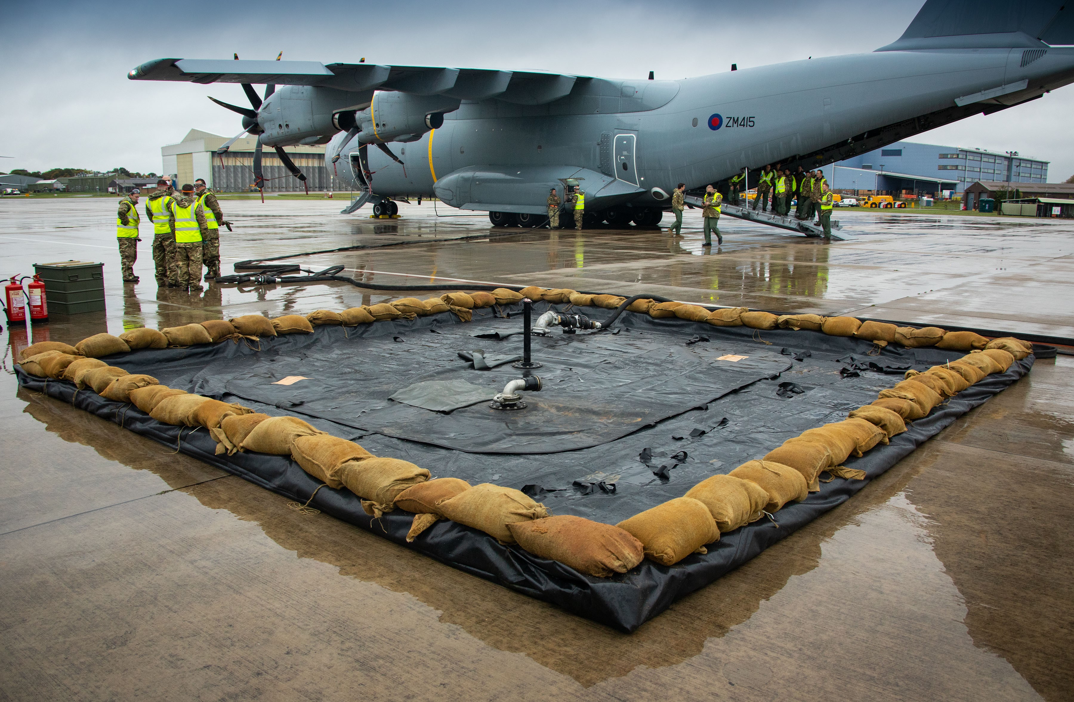 Image shows RAF aviators with Hercules aircraft and hazardous spill kit on the airfield. 